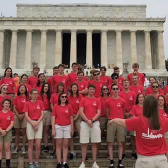 A crowd of young adults standing on steps outside a memorial