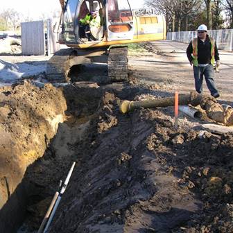 Two people digging a trench with an excavator