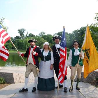 Four people in historic costumes holding flags